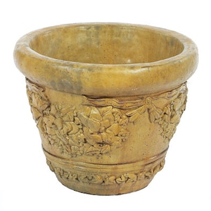 May include: A large, round, yellow terracotta planter with a detailed floral design. The planter has a wide rim and a slightly flared base.