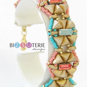 Könnte beinhalten: Goldfarbenes, türkisfarbenes und rosafarbenes Perlenarmband mit geometrischem Muster. Das Armband besteht aus einer Reihe von dreieckigen Perlen und rechteckigen Steinen.