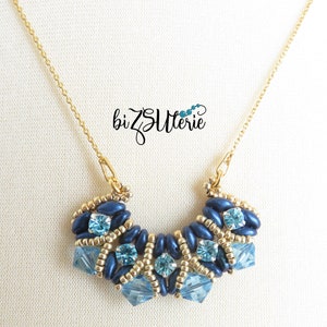 May include: A gold chain necklace with a blue and gold beaded pendant. The pendant is shaped like a crescent moon and features blue and gold beads, as well as clear crystals.
