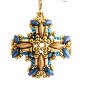 May include: Astra beaded pendant in a cross design. The pendant features gold, teal, and blue beads. The text "astra" and "beading pattern by" are at the top. The pendant is suspended from a gold-colored bail.