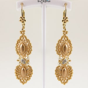 May include: Gold beaded earrings with a teardrop shape and a gold oval bead in the center. The earrings have a white pearl and a clear rhinestone bead.