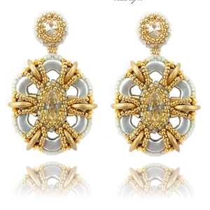 May include: A pair of gold and silver earrings with a crystal centre and a beaded design. The earrings are hanging from a small, beaded loop.