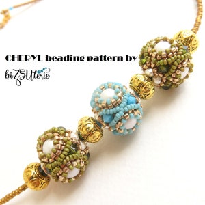 Op de afbeelding: Een gouden ketting met drie kralenbollen. De bollen zijn gemaakt van groene, blauwe en witte kralen. De ketting is gelabeld "CHERYL beading pattern by bizSutterie".
