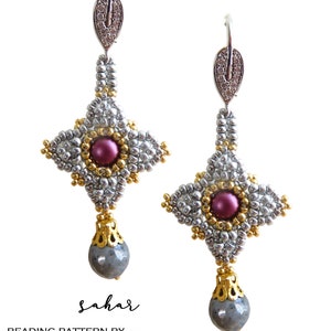 Può includere: Orecchini fatti a mano con un design di perline argentate, dorate e viola. Gli orecchini presentano una perla centrale viola, una pietra grigia a forma di goccia e un cappuccio decorativo dorato. La parola "sahar" è scritta in corsivo.