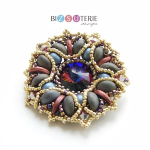 Pode incluir: Um broche de flor de contas com um centro de cristal multicolorido. O broche é feito com contas cinzas, azuis, douradas e vermelhas. O texto "BIZ SUTERIE design" é visível na parte superior central da imagem.