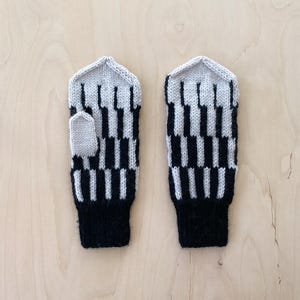 May include: A pair of black and beige knitted fingerless gloves with a geometric pattern. The gloves have a black cuff.