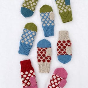 May include: A selection of knitted mittens in shades of blue, green, red, pink, and beige. Each mitten has a white dotted pattern. The mittens are displayed on a white surface.