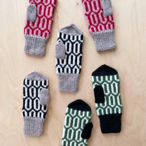 May include: A collection of six knitted mittens in various colors. The mittens feature a geometric pattern in red, black, and green, with gray and black cuffs and thumb patches. The mittens are arranged on a light wooden surface.