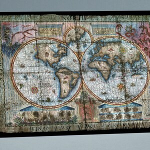May include: A vintage world map with a distressed, aged look. The map is printed on paper and framed in a black frame. The map shows the continents of North America, South America, Europe, Asia, Africa, and Australia. The map is titled "World's First Voyage of Circumnavigation 1519".