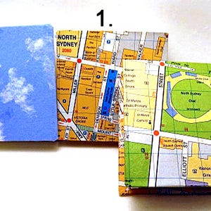 May include: Three small, square, paper-covered notebooks. The first notebook has a blue cover with white clouds. The second and third notebooks have a map of North Sydney, Australia on the cover. The second notebook shows the area around Miller Street, and the third notebook shows the area around Elliott Street.