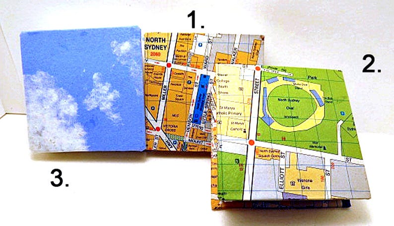 May include: Three small, square, paper-covered notebooks. The first notebook has a blue cover with white clouds. The second and third notebooks have a map of North Sydney, Australia on the cover. The second notebook shows the area around Miller Street, and the third notebook shows the area around Elliott Street.