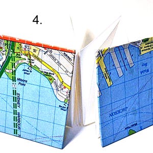 May include: A small, blue and white map notebook with a map of Sydney Harbour, Australia. The cover features the text "Milsons Point" and "Sydney Harbour".