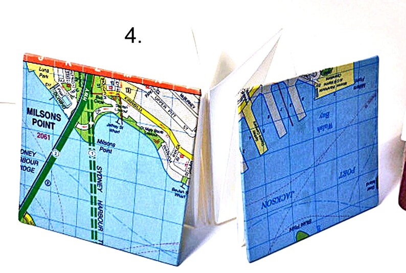 May include: A small, blue and white map notebook with a map of Sydney Harbour, Australia. The cover features the text "Milsons Point" and "Sydney Harbour".