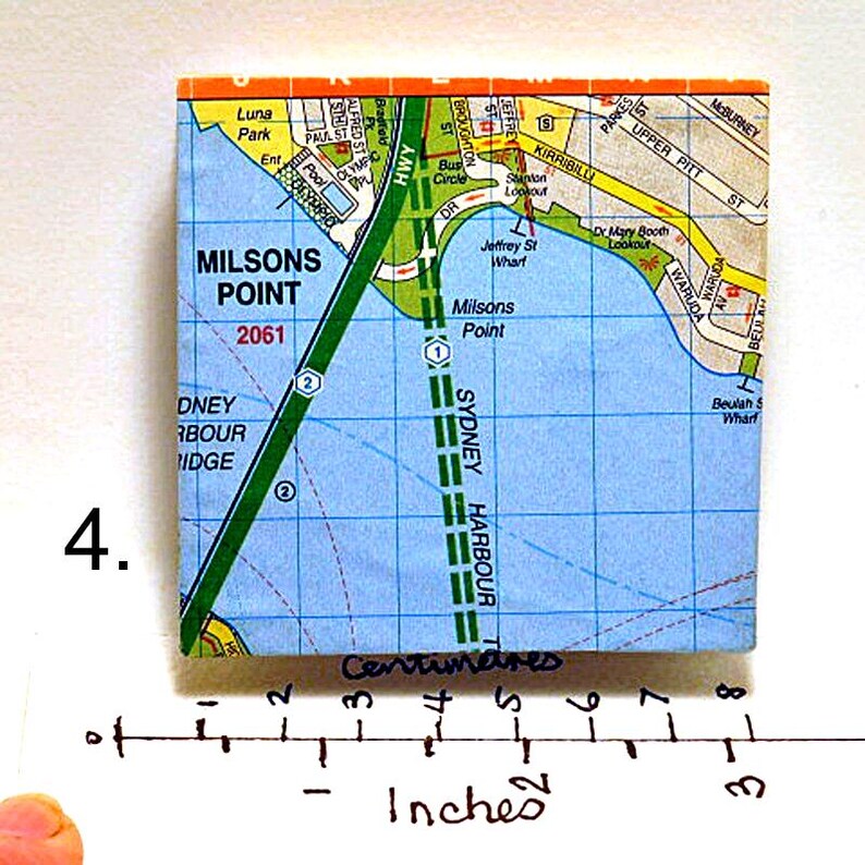 May include: A close-up of a map of Milsons Point, Sydney, Australia. The map shows the location of the Sydney Harbour Bridge, the Sydney Harbour Tunnel, and other landmarks. The map is printed on a white background with blue and green lines.