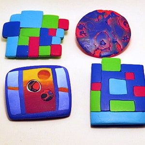 Può includere: Quattro spille geometriche in pasta polimerica colorate. Una spilla è un cerchio con un design marmorizzato blu, rosso e bianco. Le altre tre spille sono rettangolari e presentano una varietà di forme geometriche in blu, verde, rosso e giallo.