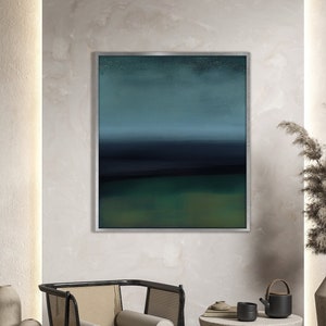 May include: A framed abstract painting with a blue, green, and black color scheme hangs on a wall above a woven rug, a chair, and a side table with a teapot and cups.