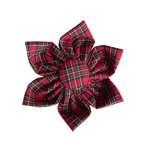 Puede incluir: Una flor de tela roja y negra a cuadros con un botón central. La flor está hecha de tela y tiene un aspecto arrugado.