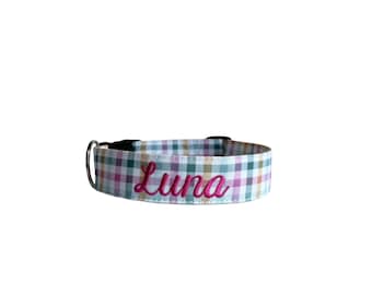 May include: A pet collar featuring a multi-colored gingham plaid pattern in shades of teal, pink, yellow, and white. The name Luna is embroidered in a cursive, dark pink thread across the center of the collar, which includes a metal D-ring.
