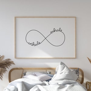 May include: A white bed with a light blue duvet and a white pillow. The bed has a wooden frame with a woven headboard. A framed print with the words "inhale exhale" in an infinity symbol is hanging on the wall behind the bed.