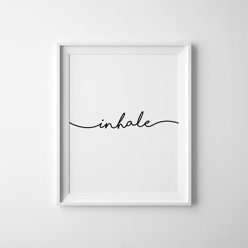 May include: A framed print with the word "inhale" in elegant black script. The word is centered on a white background, and the frame is white. The minimalist design is suitable for home decor.