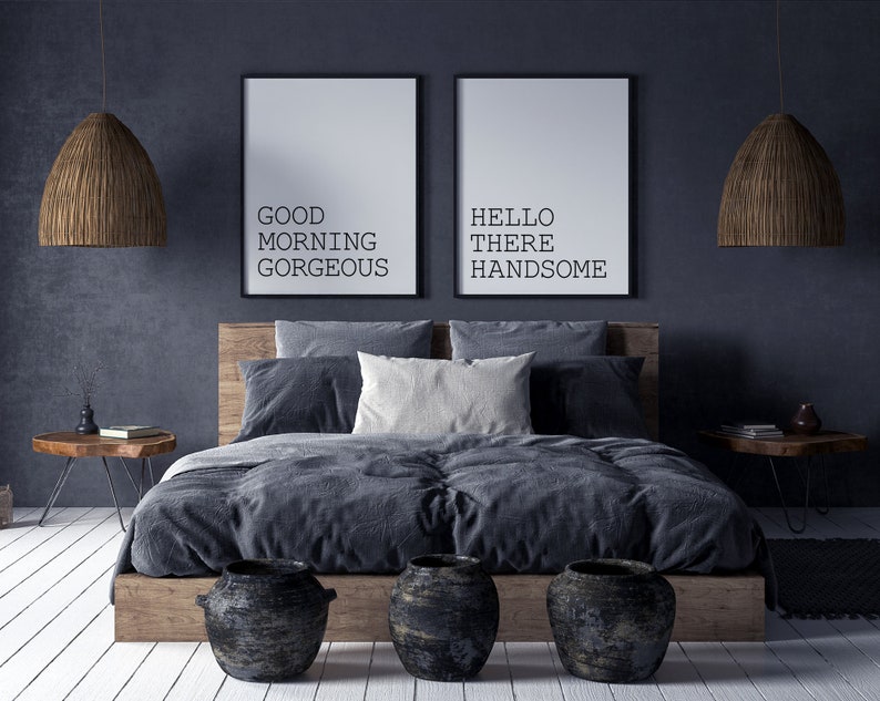 May include: A dark gray bedroom with a bed, two bedside tables, and two framed prints on the wall. The prints say "Good Morning Gorgeous" and "Hello There Handsome".