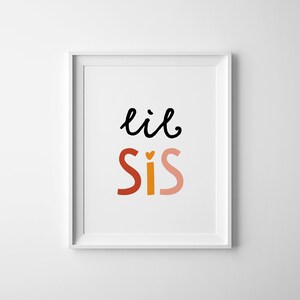 Puede incluir: Impresi&oacute;n enmarcada en blanco con el texto "lil sis" en letras negras, rojas, naranjas y rosas. La "i" de "sis" tiene un peque&ntilde;o coraz&oacute;n.