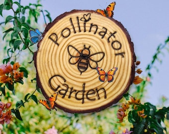 May include: A wooden sign with the words "Pollinator Garden" and a bee illustration. The sign is decorated with butterflies and a heart.