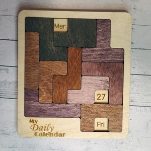 May include: A white ceramic mug with a black handle and the text "But First, Coffee" in a black, bold font. The mug is sitting on a wooden surface. The mug is 4 inches tall.