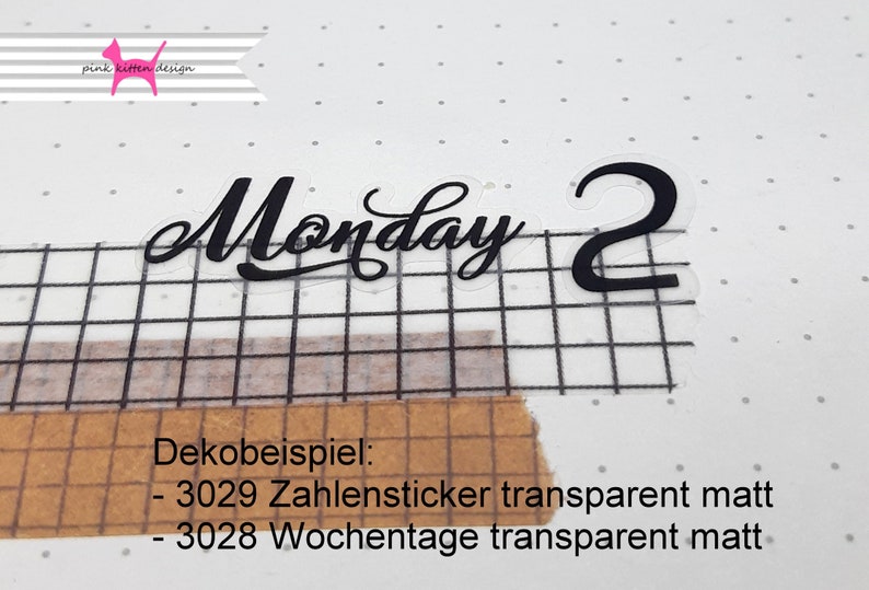 以下が含まれることがあります： 黒い文字で書かれた透明なステッカー。ステッカーには「Monday 2」と書いてあり、グリッドの背景に貼られています。ステッカーの下のテキストには「Dekobeispiel: - 3029 Zahlensticker transparent matt - 3028 Wochentage transparent matt」と書いてあります。