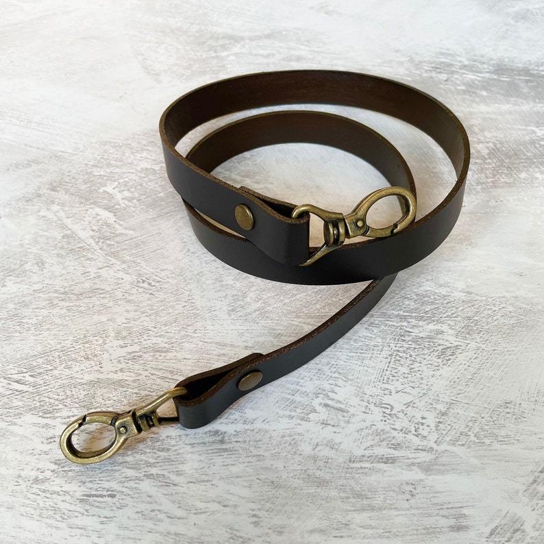 Brown leather bag strap with an antique brass lobster clasp and rivet detail