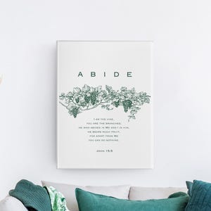 May include: A white canvas print with the word "ABIDE" in large, bold, green letters. A green vine with grapes is depicted above the text. The text below the vine reads "I am the vine, you are the branches. He who abides in me and I in him, he bears much fruit, for apart from me you can do nothing. John 15:5"