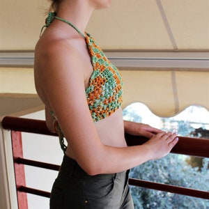 May include: A green and orange crochet halter top with a square pattern.