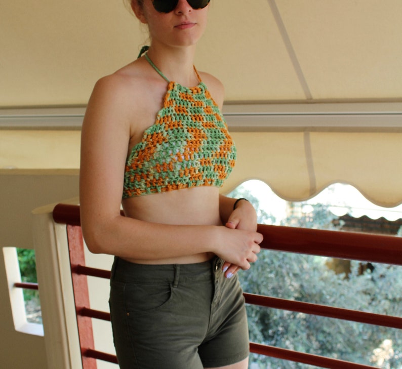 May include: A green and orange crochet halter top. The top is made with a checkered pattern.