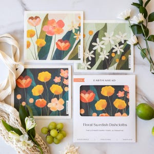 May include: A set of floral Swedish dishcloths with colorful flower designs in orange, yellow, and white. The package reads "Floral Swedish Dishcloths" and "The Ultimate Paper Towel Alternative."