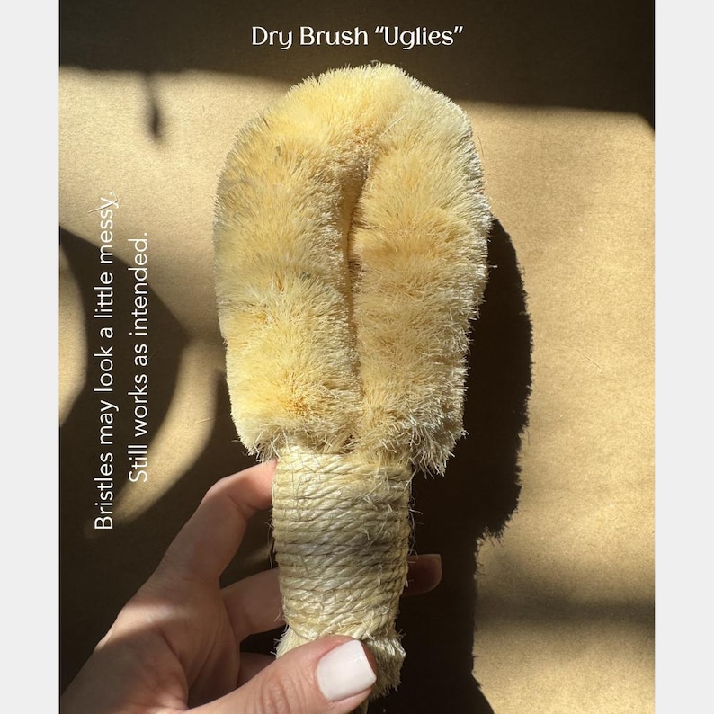 May include: A beige dry brush labeled Dry Brush Uglies with a text note stating Bristles may look a little messy. Still works as intended. The brush features a thick, rounded head of stiff, light-colored natural fibers and a handle wrapped in twine.