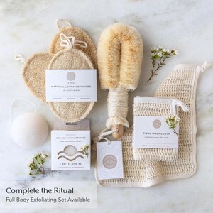 May include: A collection of bath accessories including natural loofah sponges, a long-handled body brush with tan bristles, a white konjac facial sponge, and a sisal washcloth. Each item features branded packaging with text including Natural Loofah Sponges, Konjac Facial Sponge, Earth Ahead, and Sisal Washcloth.