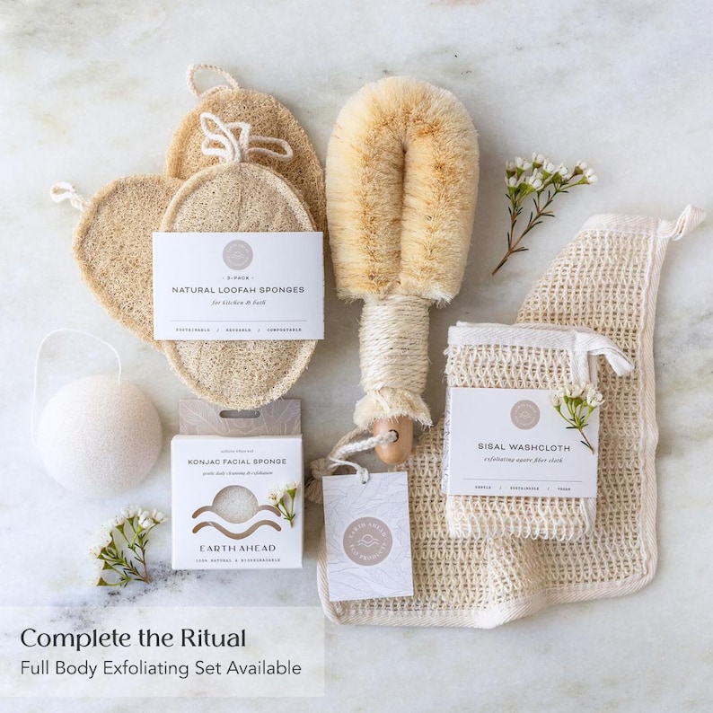 May include: A collection of bath accessories including natural loofah sponges, a long-handled body brush with tan bristles, a white konjac facial sponge, and a sisal washcloth. Each item features branded packaging with text including Natural Loofah Sponges, Konjac Facial Sponge, Earth Ahead, and Sisal Washcloth.