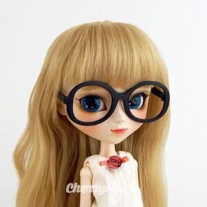May include: A doll with long blonde hair wearing black round glasses with a red flower on her white dress.