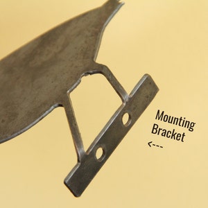 K&ouml;nnte beinhalten: Eine Metall-Montagehalterung mit zwei L&ouml;chern f&uuml;r Schrauben. Die Halterung ist mit "Montagehalterung" beschriftet.