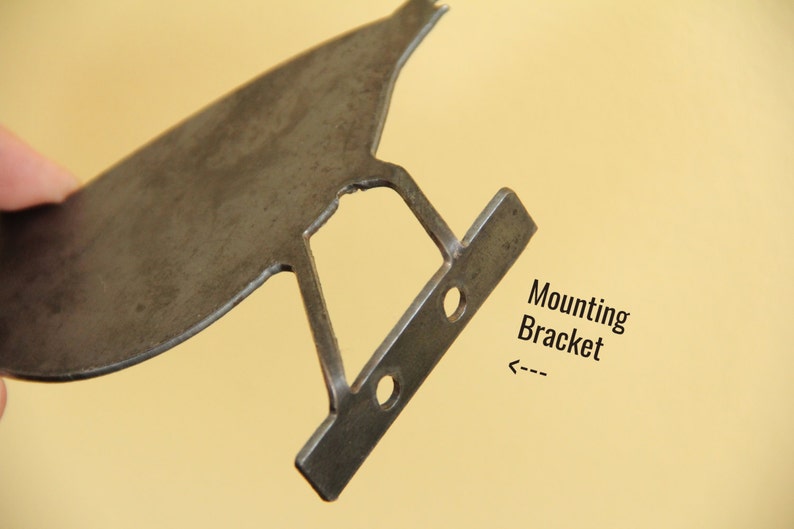 K&ouml;nnte beinhalten: Eine Metall-Montagehalterung mit zwei L&ouml;chern f&uuml;r Schrauben. Die Halterung ist mit "Montagehalterung" beschriftet.