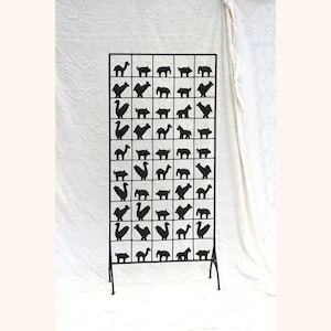 May include: Black metal room divider with a grid pattern featuring various animal silhouettes. The divider has a simple, modern design and is freestanding.