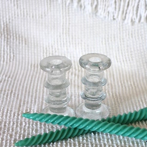 Puede incluir: Dos candelabros de vidrio transparente con un diseño texturizado y un par de velas verdes retorcidas.