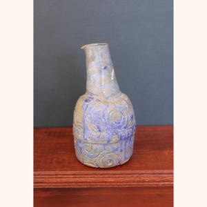 Puede incluir: Un jarrón de cerámica azul y marrón con una superficie texturizada y un diseño de espiral.