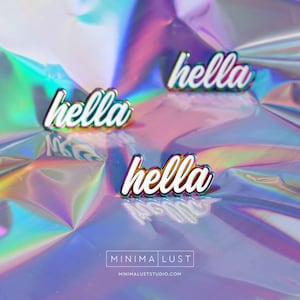 May include: Four enamel pins with the word "hella" in white script with a silver outline. The pins are arranged on a holographic, iridescent surface. The pins are a fashion accessory.