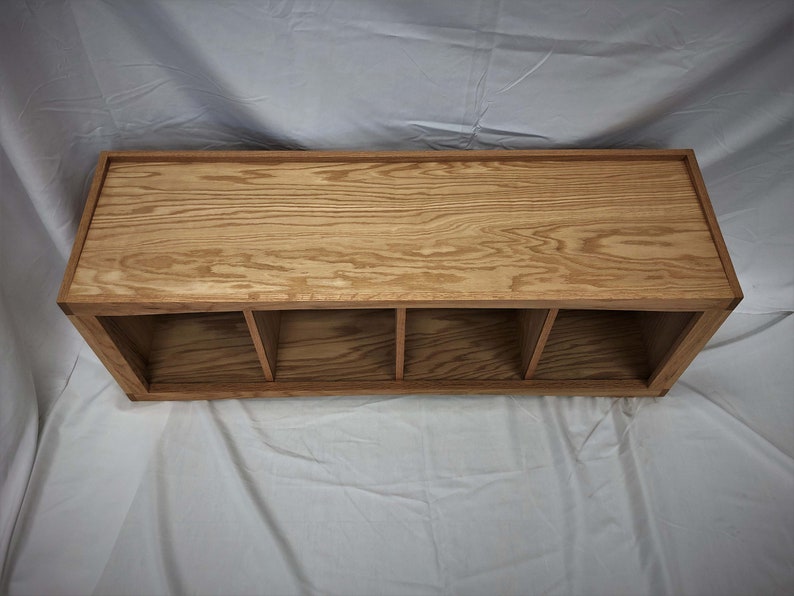 May include: A wooden shelf unit with four compartments. The shelf is made of light brown wood with a natural finish.