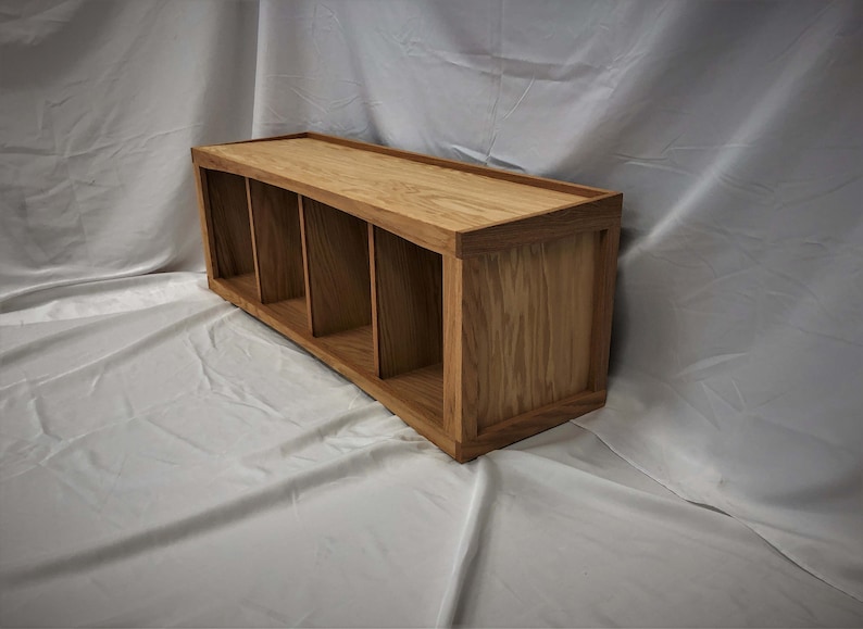 May include: A wooden shelf unit with four compartments. The shelf is made of light brown wood with a natural finish.