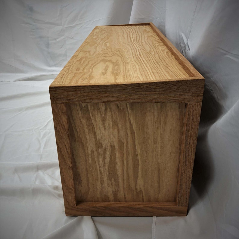 May include: A wooden storage box with a light brown finish. The box has a simple design with a rectangular shape and a flat top.
