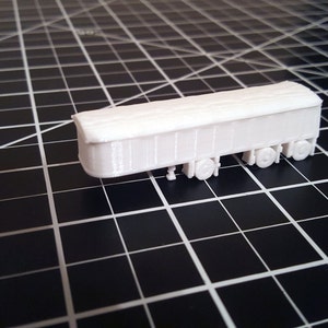 May include: A white plastic model of a boxcar with a flat roof and four wheels.