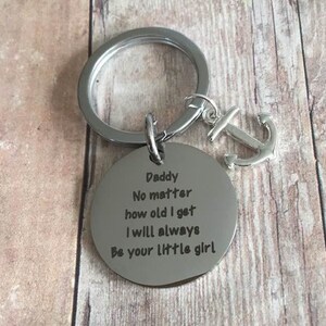 May include: Silver keychain with an anchor charm and a round tag that reads "Daddy No matter how old I get I will always Be your little girl".