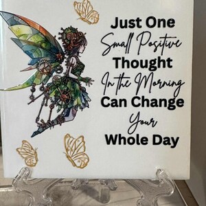 May include: A white ceramic tile featuring a steampunk fairy illustration with colorful wings and gears, accompanied by gold butterflies. The tile has the text: "Just One Small Positive Thought In the Morning Can Change Your Whole Day."